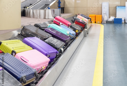 Multicolored suitcases on luggage conveyor belt in airport photo