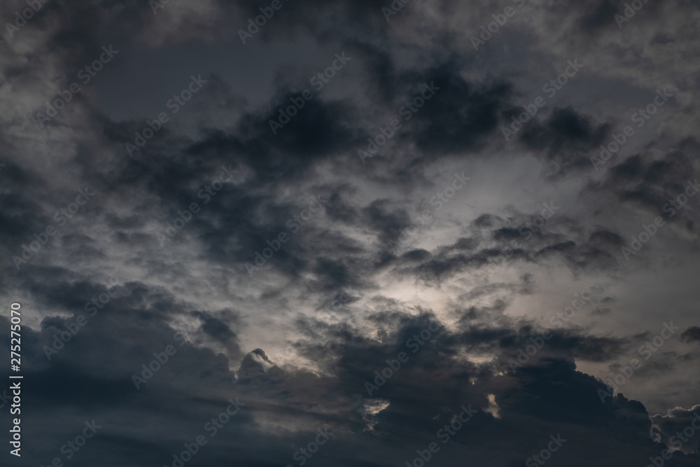 Fototapeta premium Beautiful evening skyscape. Sun's rays shine through hole in black clouds after rain, natural background.