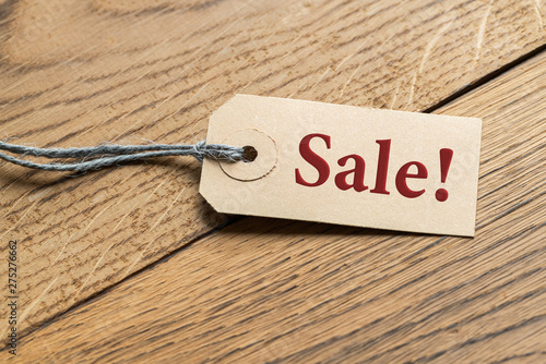 Hangtag with the word SALE! on wooden background