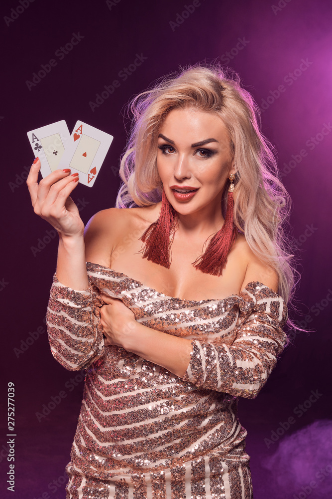 Blonde woman with a perfect hairstyle and bright make-up is posing with playing cards in her hands. Casino, poker. Blonde woman with a perfect hairstyle and bright make-up is posing with playing cards in her hands. Casino, poker.