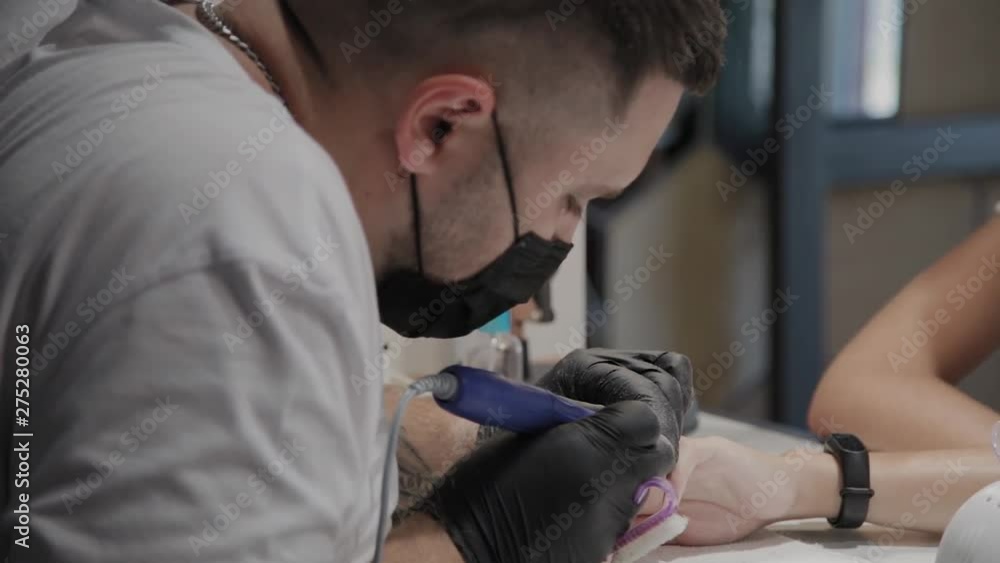 Professional manicurist man removes old nail polish from a girl using a special nail polish remover. Professional manicurist man removes old nail polish from a girl using a special nail polish remover.