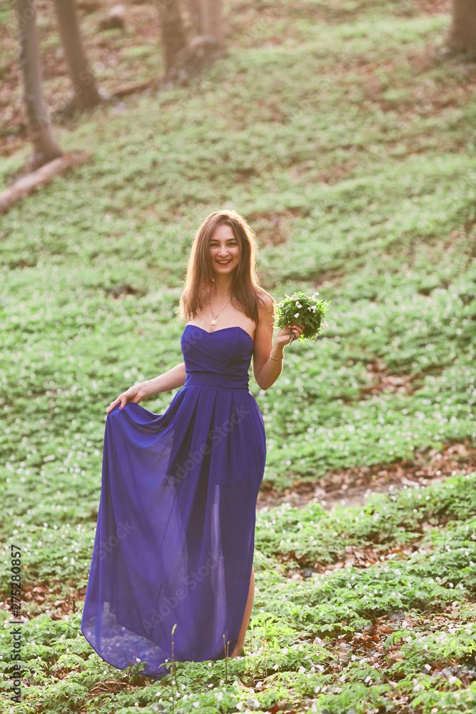 Happy girl in a long blue dress goes through the woods Happy girl in a long blue dress goes through the woods