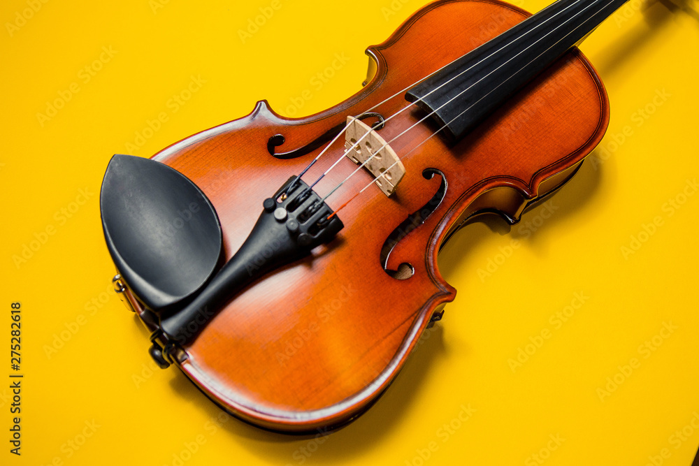 Fototapeta premium Violin with bow isolated on a yellow background. Types of musical instrument