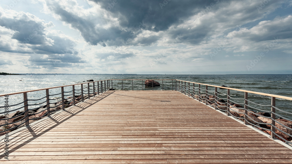 Perspective view at sea from center of wooden pier made of deck board  with posts and ropes. Dramatic sky at daylight. Vintage toning