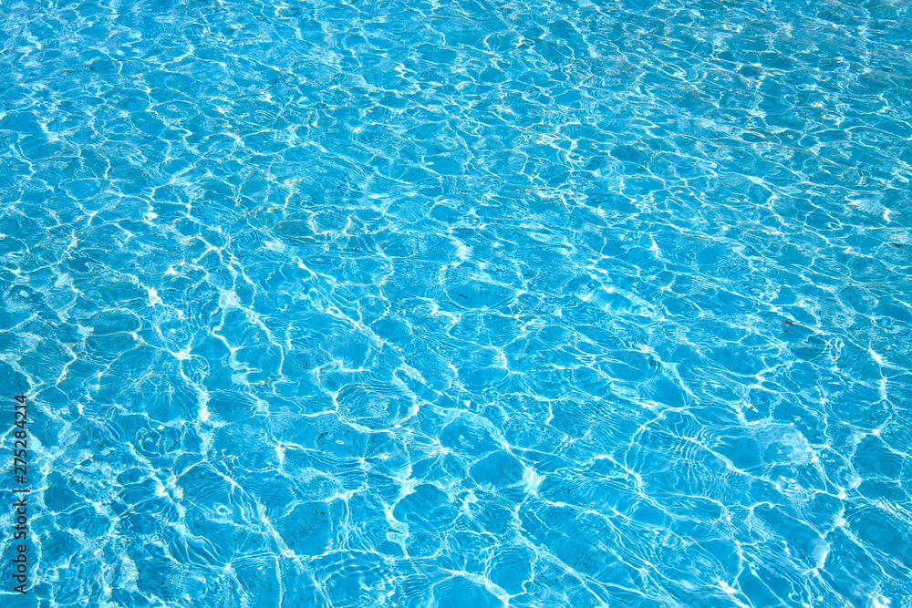 Blue color water in swimming pool rippled water with sun reflections background.