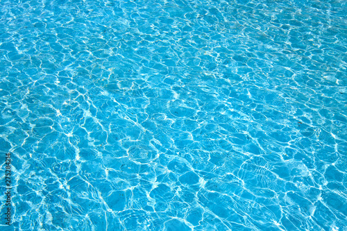 Blue color water in swimming pool rippled water with sun reflections background.