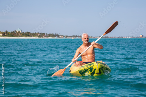 Elder fit man is kayaking on a bright yellow kayak in Caribbean Sea during a sunny summer day. Taken in Varadero, Cuba. © edb3_16