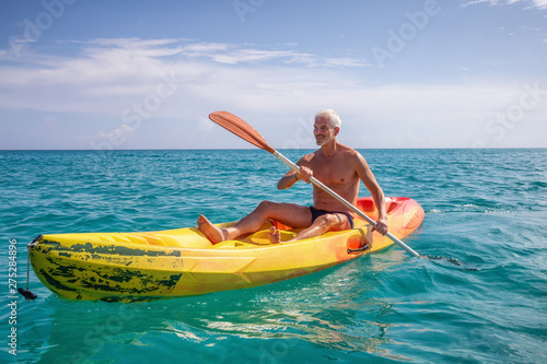 Elder fit man is kayaking on a bright yellow kayak in Caribbean Sea during a sunny summer day. Taken in Varadero, Cuba. © edb3_16