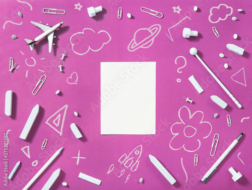Back to school concept. White accessories and chalk drawings on pink background with blank paper in the middle.