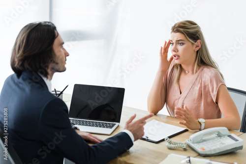 Фотография upset woman sitting in office and talking with businessman