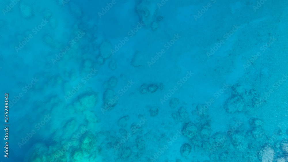 Blue sea water texture aerial drone view. Blue lagoon water surface. Rocks underwater.