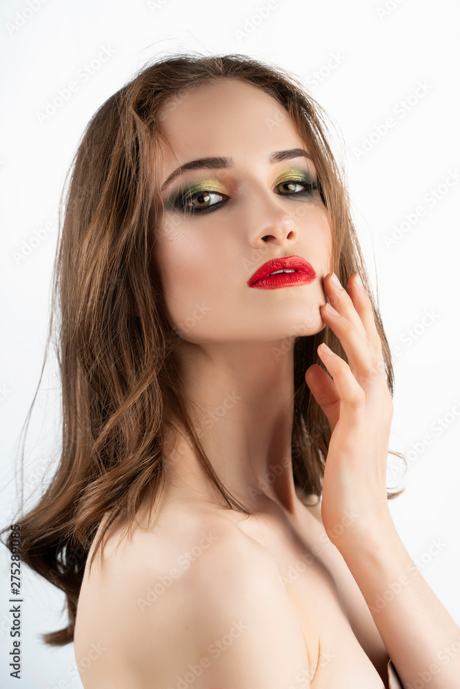 Beautiful girl model with red lips make-up and naked shoulders smiles and sensually touches face with her fingers. Isolated on white Beautiful girl model with red lips make-up and naked shoulders smiles and sensually touches face with her fingers. Isolated on white