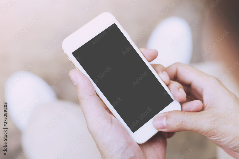 Close up of a young man hand holding using mobile smart phone with screen empty cell phone. he sitting chair in public park outdoor. Top view with copy space.