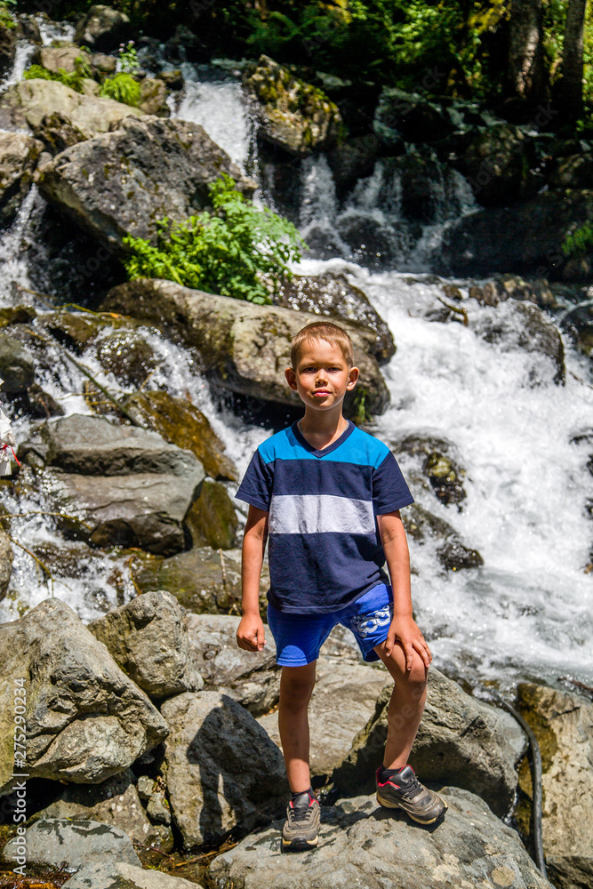 boy standing on a rock by the waterfall