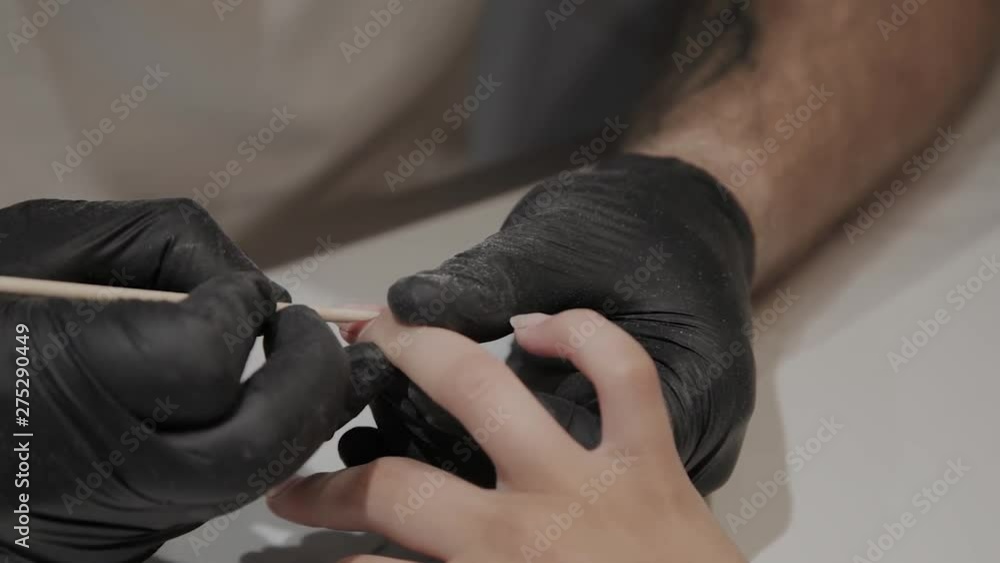 Professional manicurist man raises cuticles for further udvivaniya special tool. Professional manicurist man raises cuticles for further udvivaniya special tool.