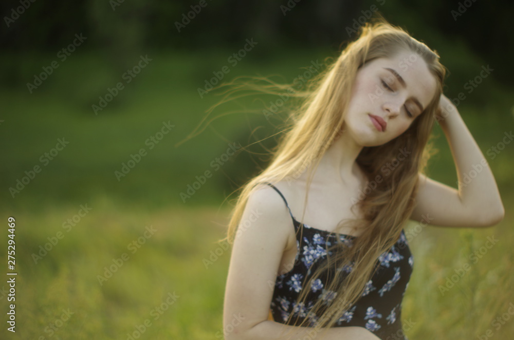  beautiful young blonde with long flowing hair on a blurred background of summer greenery