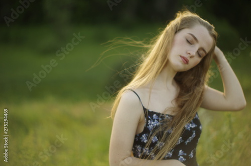  beautiful young blonde with long flowing hair on a blurred background of summer greenery © Panas
