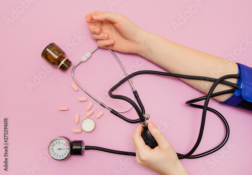 Measurement of pressure. The woman takes care of her health by checking her blood pressure and pulse on her arm. lilac background