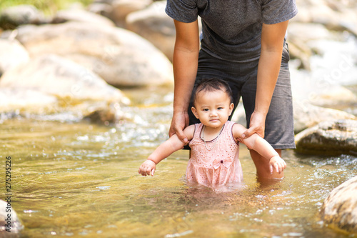 Man holding his baby daughter walking in shallow water
