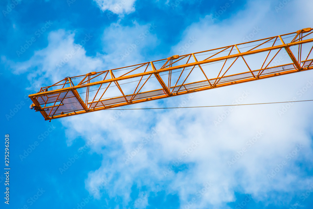 Concept photo of building construction, construction, orange cranes and scaffolding on a bright sunny day against the blue sky.