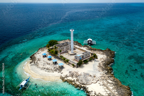 Aerial drone view of a lighthouse on a tiny tropical island surrounded by coral reef and deep water (Capitancillo Island, Cebu, Philippines) photo