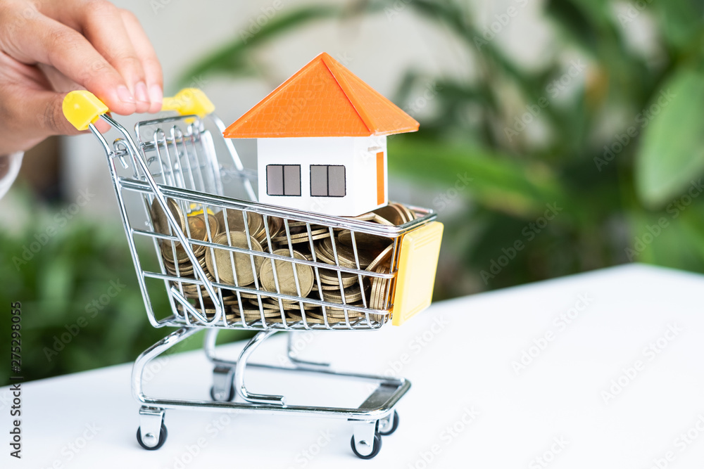 House  orange roof and coin in the shopping cart.House model in mini shopping cart with stack of coins money  for residential investment.Home and real estate mortgage concept.With text input area.