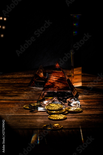 Dark moody wooden table with bitcoins, cryptocurrency and prism glass and jewelry 