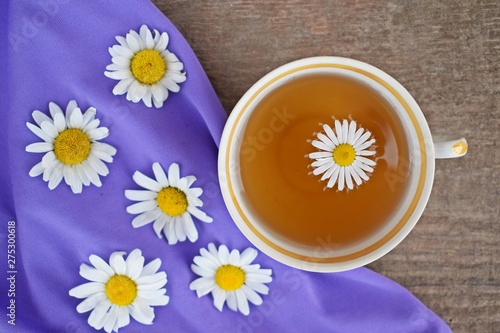 Fresh chamomile flowers and healthy tea on a lilac background.Alternative medicine.