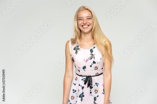 Portrait of a cute beautiful pretty woman girl with long beautiful hair on a white background in a pink dress with a pattern. Shows many different emotions, smiles and talks. Made in a studio. © Вячеслав Чичаев