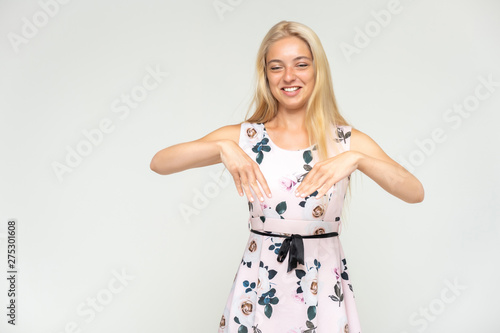 Portrait of a cute beautiful pretty woman girl with long beautiful hair on a white background in a pink dress with a pattern. Shows many different emotions, smiles and talks. Made in a studio. © Вячеслав Чичаев