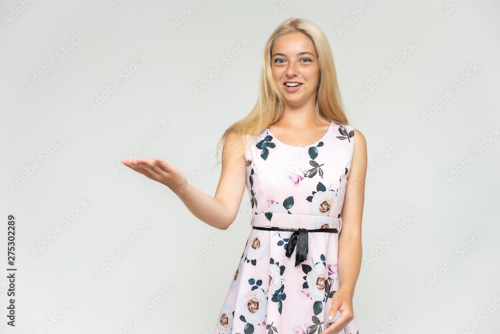 Portrait of a cute beautiful pretty woman girl with long beautiful hair on a white background in a pink dress with a pattern. Shows many different emotions, smiles and talks. Made in a studio. Portrait of a cute beautiful pretty woman girl with long beautiful hair on a white background in a pink dress with a pattern. Shows many different emotions, smiles and talks. Made in a studio.