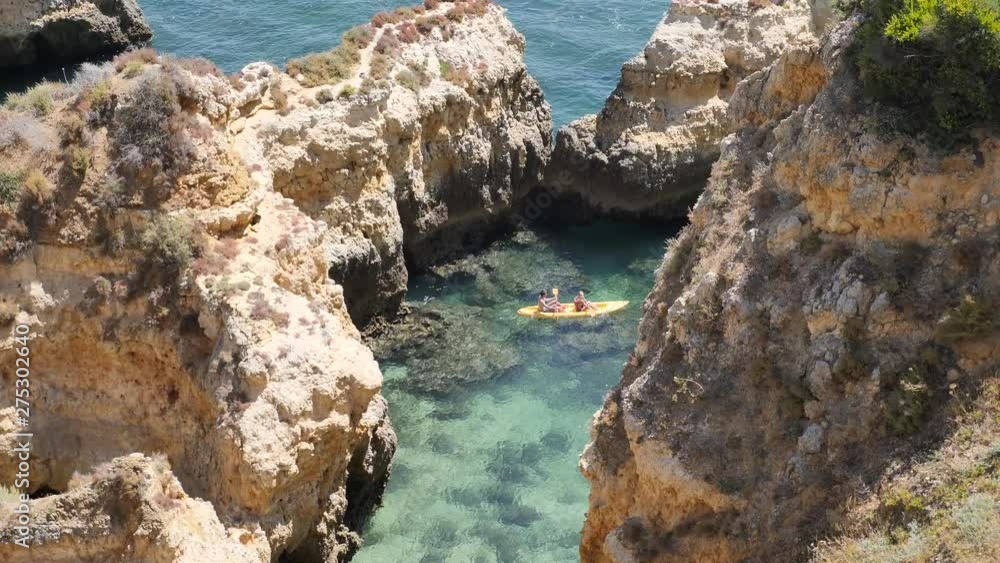 Two people in the kayak exploring the rock formations on the Algarve coast. Portugal. Flat plane. High angle shot Two people in the kayak exploring the rock formations on the Algarve coast. Portugal. Flat plane. High angle shot
