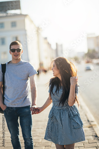 Happy young couple in love teenagers friends dressed in casual style walking together on city street