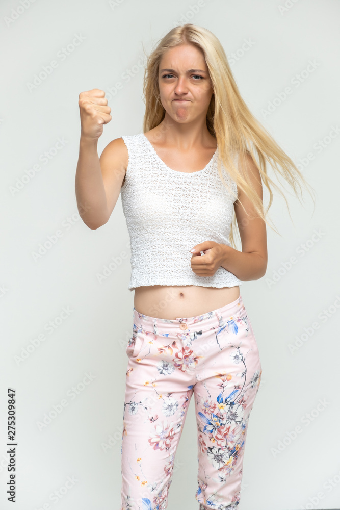 Portrait of a cute beautiful pretty woman girl with long beautiful hair on a white background in pink pants with a pattern. Shows many different emotions, smiles and talks. Made in a studio. Portrait of a cute beautiful pretty woman girl with long beautiful hair on a white background in pink pants with a pattern. Shows many different emotions, smiles and talks. Made in a studio.