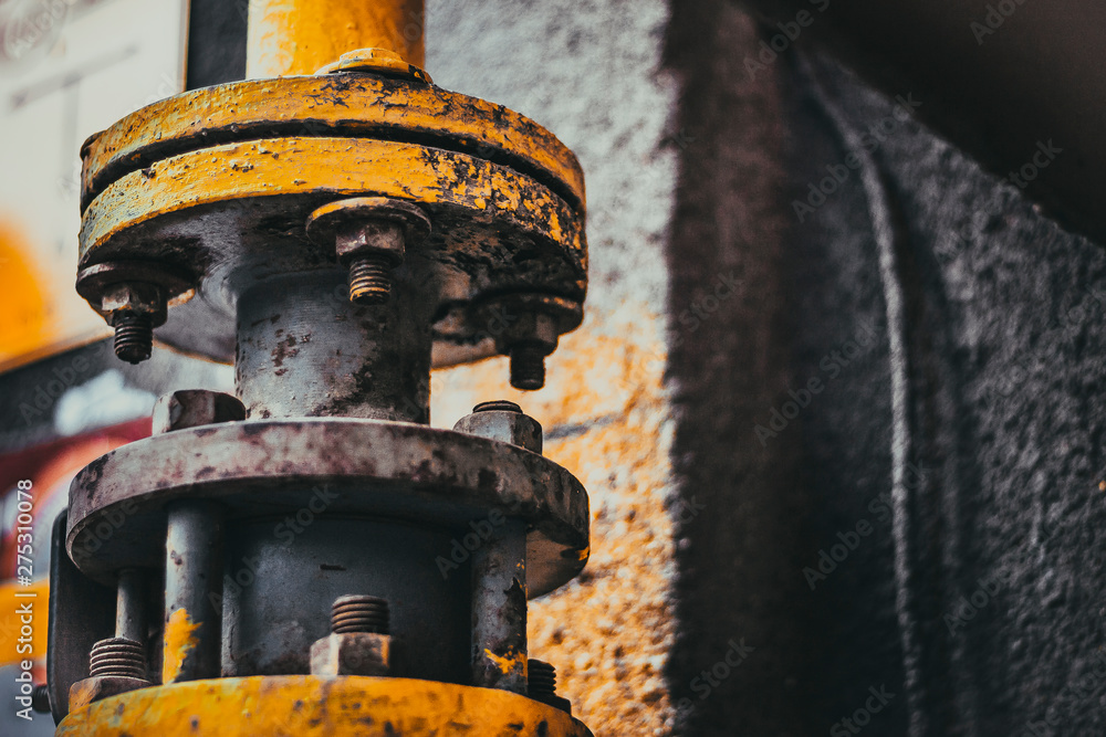 pipe with bolts on the gray wall; yellow flaky paint and rust on the pipe pipe with bolts on the gray wall; yellow flaky paint and rust on the pipe