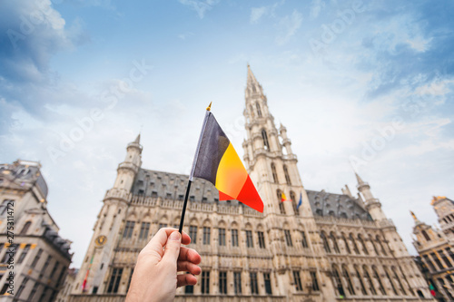 Woman tourist holds in her hand a flag of Belgium against the background of the Grand-Place Square in Brussels  Belgium