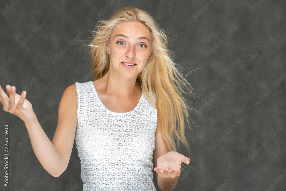 Portrait of a cute beautiful pretty woman girl with long beautiful hair on a dark gray background in a white sweater with a pattern. Shows many different emotions, smiles and talks. Made in a studio. Portrait of a cute beautiful pretty woman girl with long beautiful hair on a dark gray background in a white sweater with a pattern. Shows many different emotions, smiles and talks. Made in a studio.
