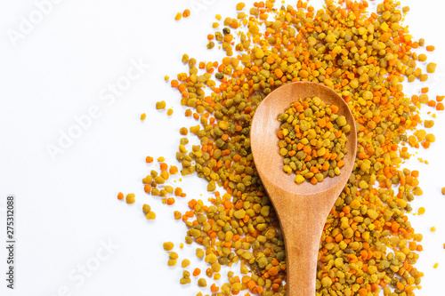 Bee pollen grains with wooden spoon on white