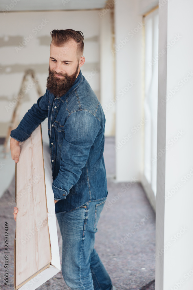 Obraz premium Mann auf einer Baustelle trägt Dielen für den Fußboden
