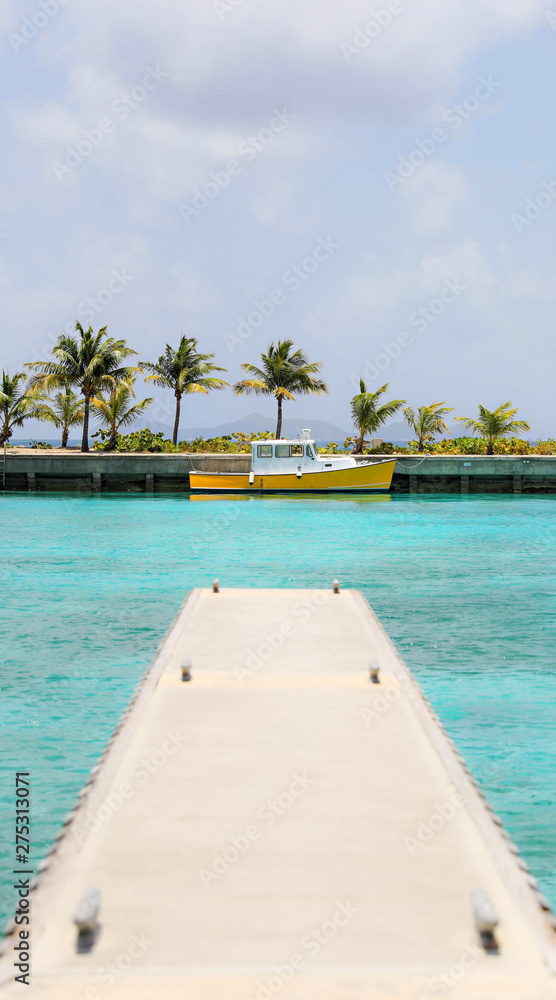 Little yellow boat at the end of a dock in the caribbean. 