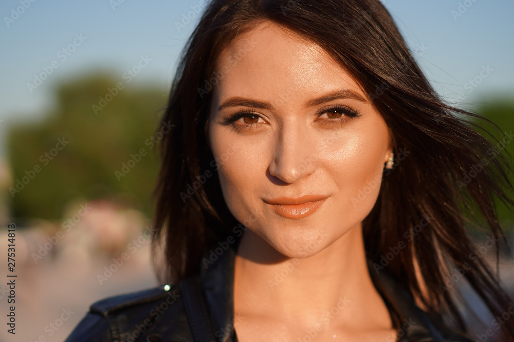 Fototapeta premium Beautiful dark-haired girl in a leather jacket smiles.