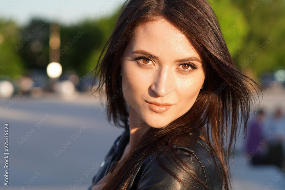 Street close-up portrait of a beautiful brunette in a black leather jacket. Street close-up portrait of a beautiful brunette in a black leather jacket.