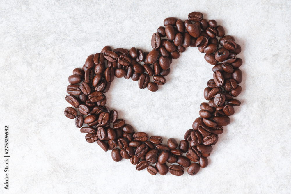 Heart made from dark brown coffee beans on a light grey background. Heart made from dark brown coffee beans on a light grey background.