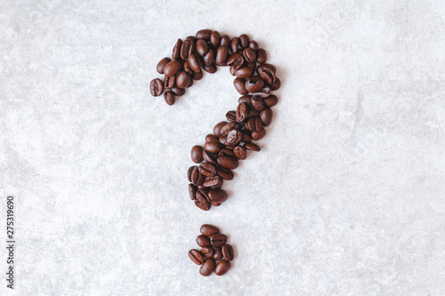 Question mark made from dark brown coffe beans on a light grey background.
