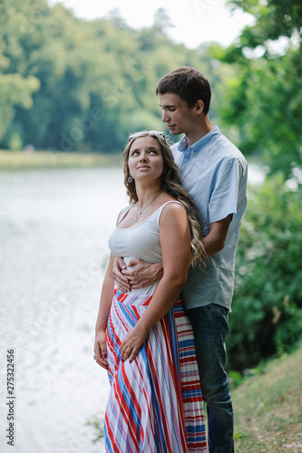 Young loving couple hugging, embracing each other tenderly at beautiful place by the river