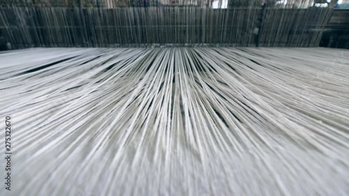 Industrial textile factory. Close up of thick white threads moving through the loom photo