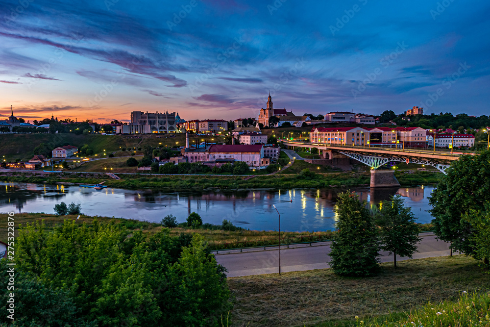 panorama view on evening in old town on the bank of wide river with evening fluffy curly rolling cirrostratus clouds and blue violet red sunset sky as background