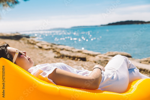 woman resting at yellow inflatable air sofa at the sea beach in sunny day