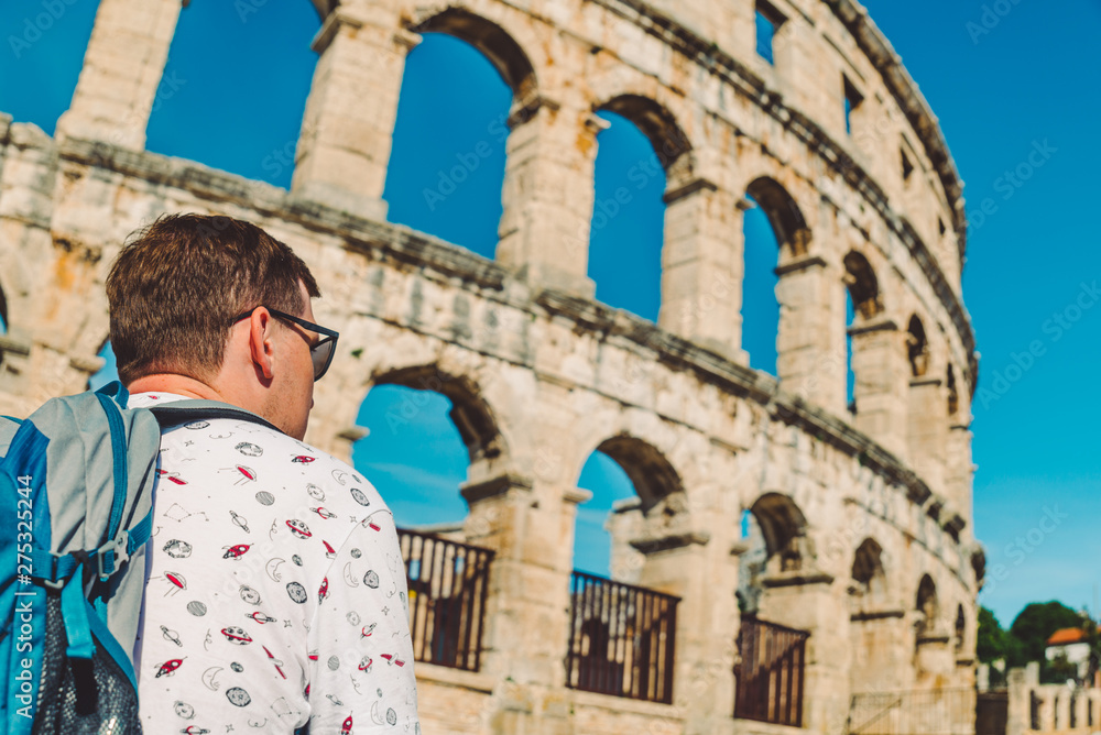 young man tourist standing near old roman coliseum in pula croatia. tourism concept