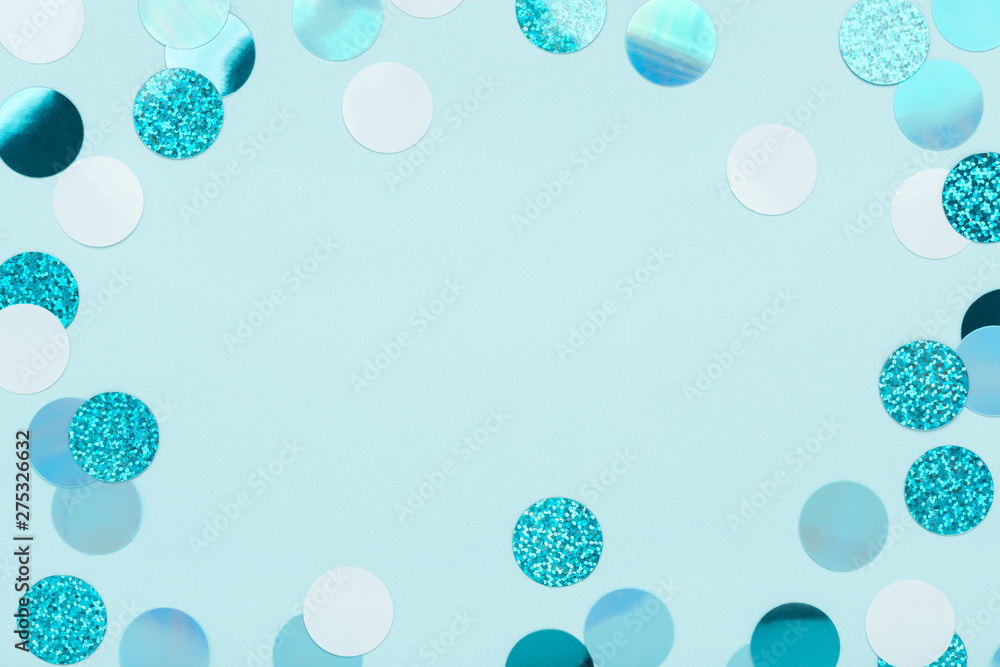 Festive frame of iridescent confetti sparkling on pastel blue background. Holiday backdrop. Flat lay, copy space. - obrazy, fototapety, plakaty 